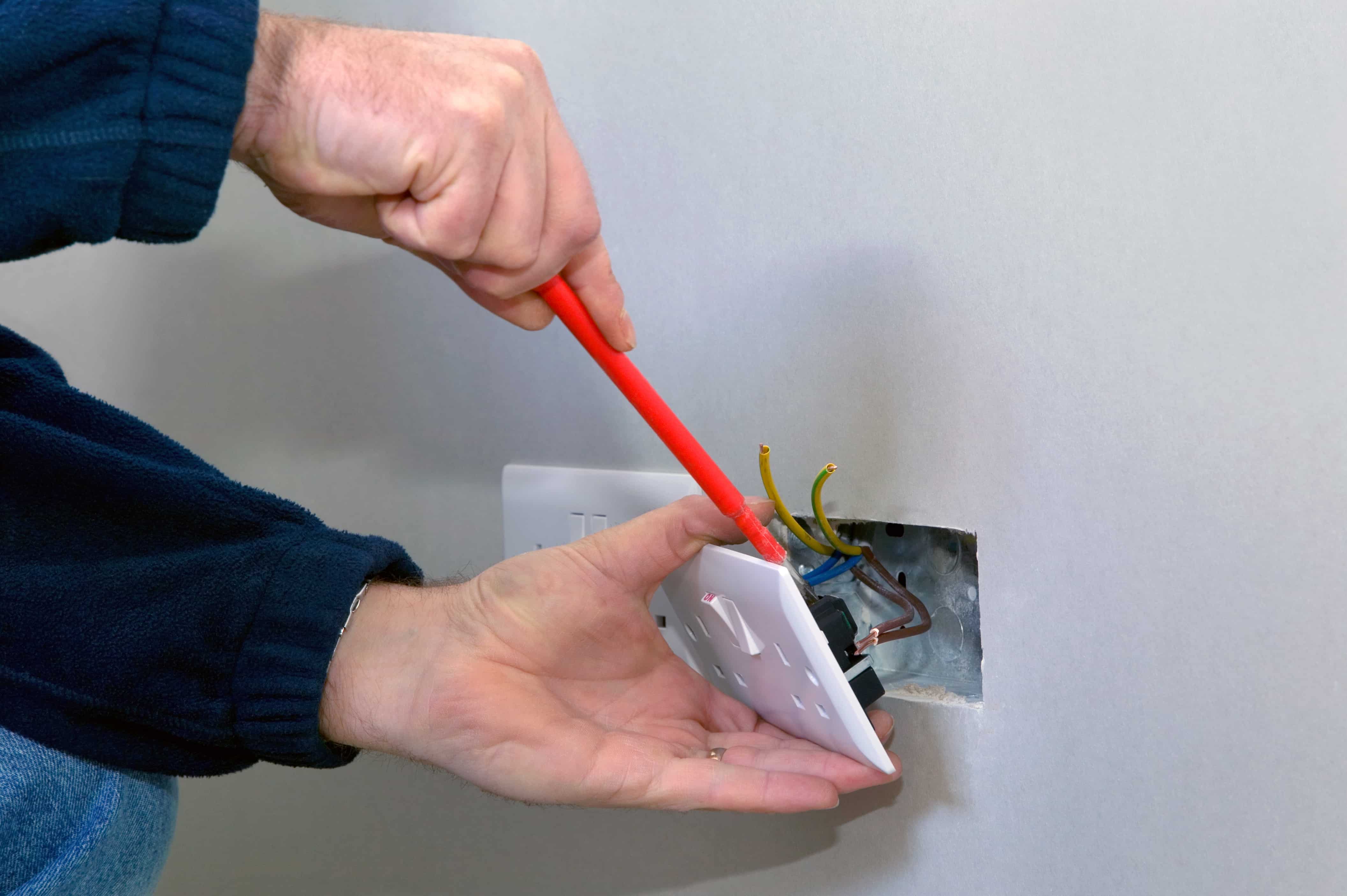 Person Taking Socket off Wall during Energy Consultancy and Compliance Management Check